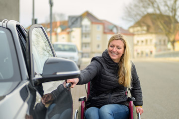 Woman in a wheelchair opening a car door