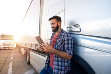 Professional truck driver checking his route on tablet computer and standing by long vehicle. Transportation service. © littlewolf1989
