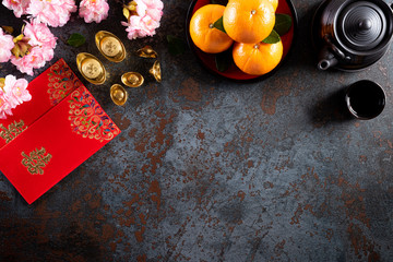 Chinese new year festival decorations pow or red packet, orange and gold ingots or golden lump on a black stone texture background. Chinese characters FU means fortune good luck, wealth, money flow.
