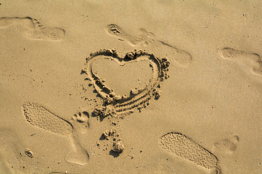 Shape of the heart and footprints in the sand on the beach. Vacation in Greece.