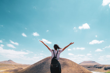 woman is standing front of a hill with wide open arms