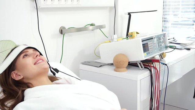 Beauty salon. Young attractive girl in a cosmetic salon lying on the table takes electro therapy.