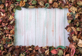 light wood vintage background decorated with a scarlet rose in a frame of dry multi-colored flowers, there is room for text