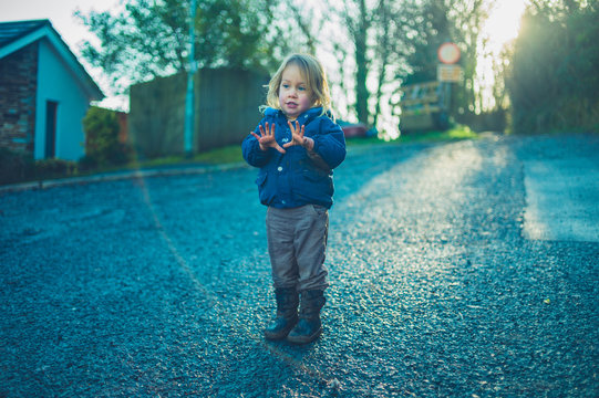 Little toddler standing in the street at sunset