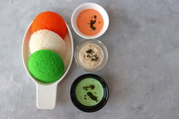 Tiranga Idli or Tricolor Idly cooked in  Indian National Flag colors - saffron or orange, white and green. Served with tiranga chutney. Concept for Indian Independence or Republic day greeting card. 