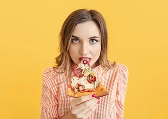 Fotobehang Portrait of beautiful young woman eating pizza on color background © Pixel-Shot