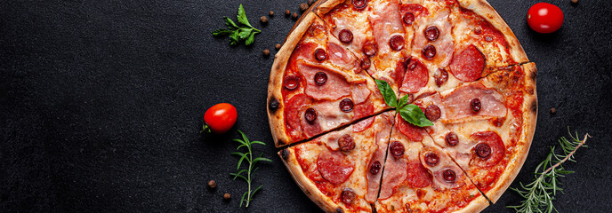 Italian Cuisine. Pepperoni pizza with salami sausage and red hot pepper, lies on a wooden board, on...