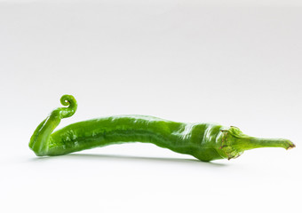 Long thin curly green pepper on a white background.. - 315575779