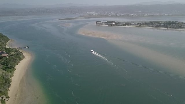Tour boat stays in deep channel returning to port in Knysna, aerial