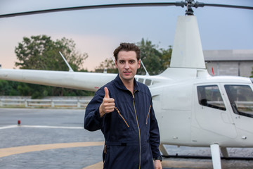 Commercial man pilot in technician suit standing in front of helicopter after check and maintenance engine 