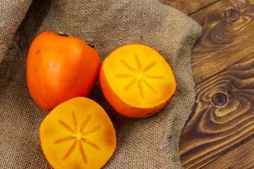 Tasty ripe persimmon fruits on a wooden table