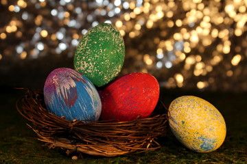 beautiful multicolored Easter eggs in a wicker basket on a shiny background
