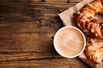 Delicious pastries and coffee on wooden table, flat lay. Space for text