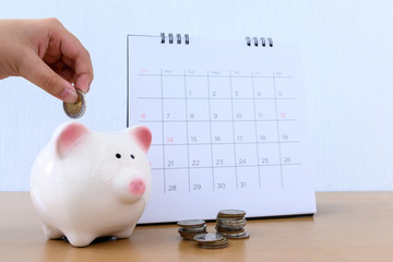 calendar and Child hand putting coin money in piggybank
