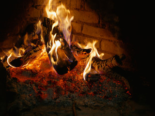The tree burns in the fireplace. flame in the fireplace. low key. large view