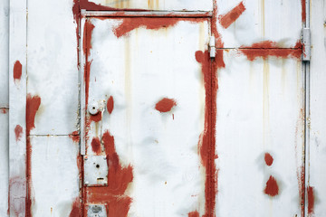 Painted in white and red old damaged iron door and wall texture, wallpaper and background. Grunge rustic design, decoration and exterior or interior details concept