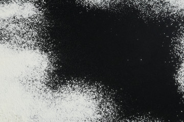 Flour on black table, top view. Space for text