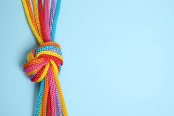 Fotobehang Top view of colorful ropes tied together on light blue background, space for text. Unity concept © New Africa