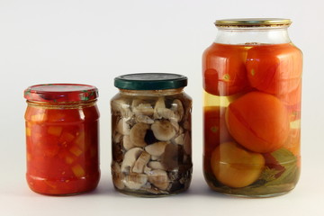 Tasty preserved vegetables mix, pickled paprika, and canned potatoes in a glass jars with metal caps on white background, ecological homemade pickles