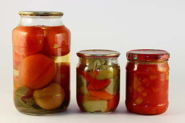 Fototapeta na wymiar Juicy pickled vegetables potatoes, canced paprika and preserved salad mix in a glass jars with metal lids on white background, natural homemade pickles