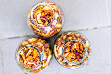 Dehydrated dry orange homemade pieces apple fruit slices in many glass jars flat top lay view down