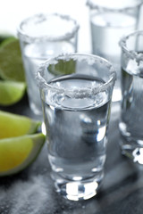 Mexican Tequila shots, lime slices and salt on grey table, closeup