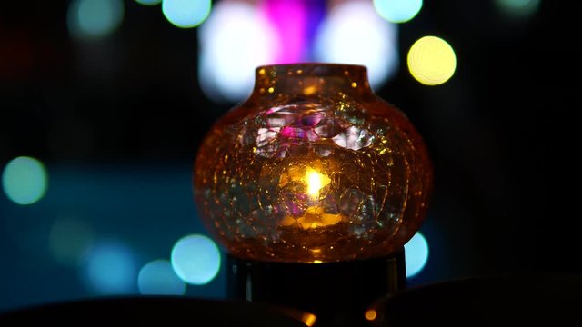 Magic lantern. Glass lamp with a candle Against the background of the defocused image of the pool party.