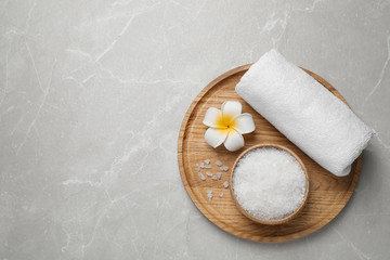 Sea salt, towel and flower on grey marble table, top view with space for text. Spa treatment