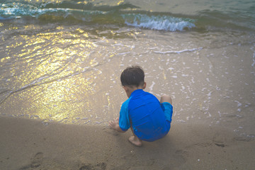 A boy is playing sand and swimming with his brother on the beach.