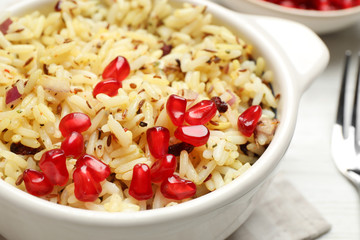 Tasty rice pilaf with pomegranate grains on table, closeup