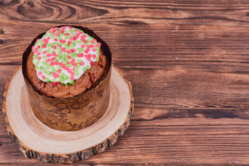 Easter composition. Easter cake on a stand made of a slice wood on a dark wooden background. With copy space