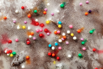 Sugar colored confetti lies on a white icing cake, texture of sugar icing on a cupcake surface close-up, pink, blue and white candy