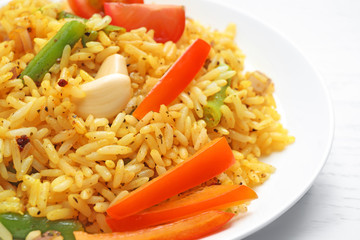 Tasty rice pilaf with vegetables on white wooden table, closeup