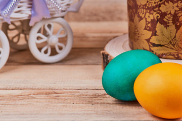 Easter composition. Easter cake on a stand made of a slice wood next to colorful Easter eggs on a wooden background. With copy space
