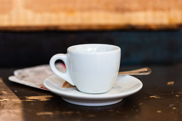 Macro closeup of espresso cappuccino coffee cup on plate saucer and background table in Italy cafe breakfast
