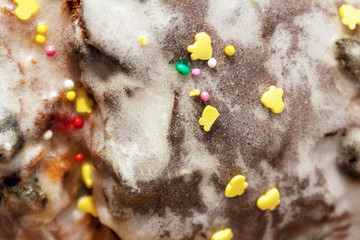 Sugar colored confetti lies on a white icing rustic cake, texture of sugar icing on a cupcake surface close-up, pink, blue and white candy