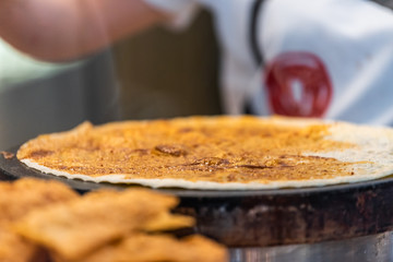 Closeup of person cooking crepe or cinnamon tortilla in Florence, Italy in famous market