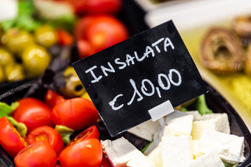 Macro closeup of packaged salad display with tomatoes, olives and feta cheese in famous Florence Italy Firenze Centrale Mercato with sign for expensive price