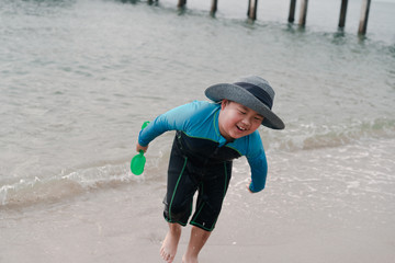 A boy is playing sand and swimming with his brother on the beach.