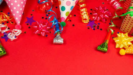 Festive golden and purple stars of confetti  and a present, birthday caps on a red background.