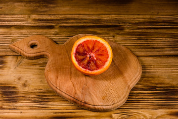 Cutting board with halved sicilian orange on a wooden table