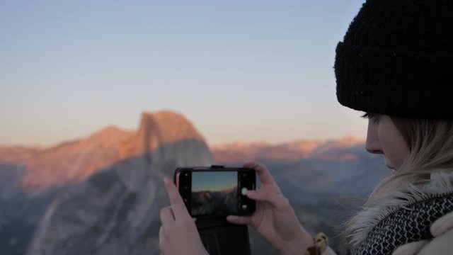 Young traveling woman using smart device camera to take photos Yosemite 
