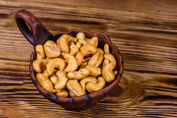 Ceramic bowl with roasted cashew nuts on a wooden table