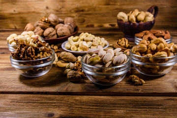 Various nuts (almond, cashew, hazelnut, pistachio, walnut) in bowls on a wooden table. Vegetarian meal. Healthy eating concept
