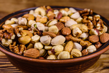 Various nuts (almond, cashew, hazelnut, pistachio, walnut) in ceramic plate on a wooden table. Vegetarian meal. Healthy eating concept