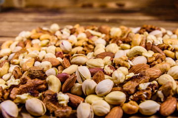 Background of the various nuts (almond, cashew, hazelnut, pistachio, walnut) a wooden table. Vegetarian meal. Healthy eating concept