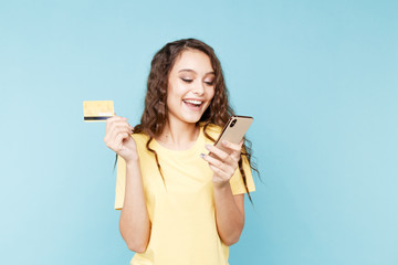 Young woman holding phone in the studio and making shopping online