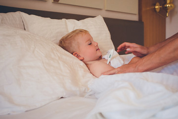 The boy lies in bed and measures the temperature