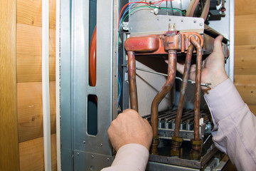 worker installs the heat exchanger after descaling on a workplace in the gas boiler