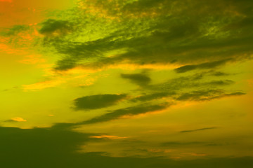 Sunset over green field and soft clouds.